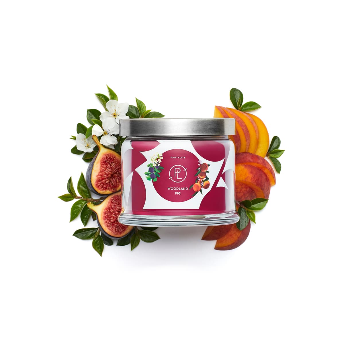 Woodland Fig 3-Wick Jar Candle with surrounding fruit and leaves decorating against a white background.