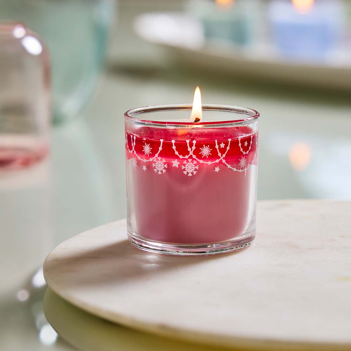 Balsam Rose Mini Jar Candle lit on a wooden surface with a blurred background.