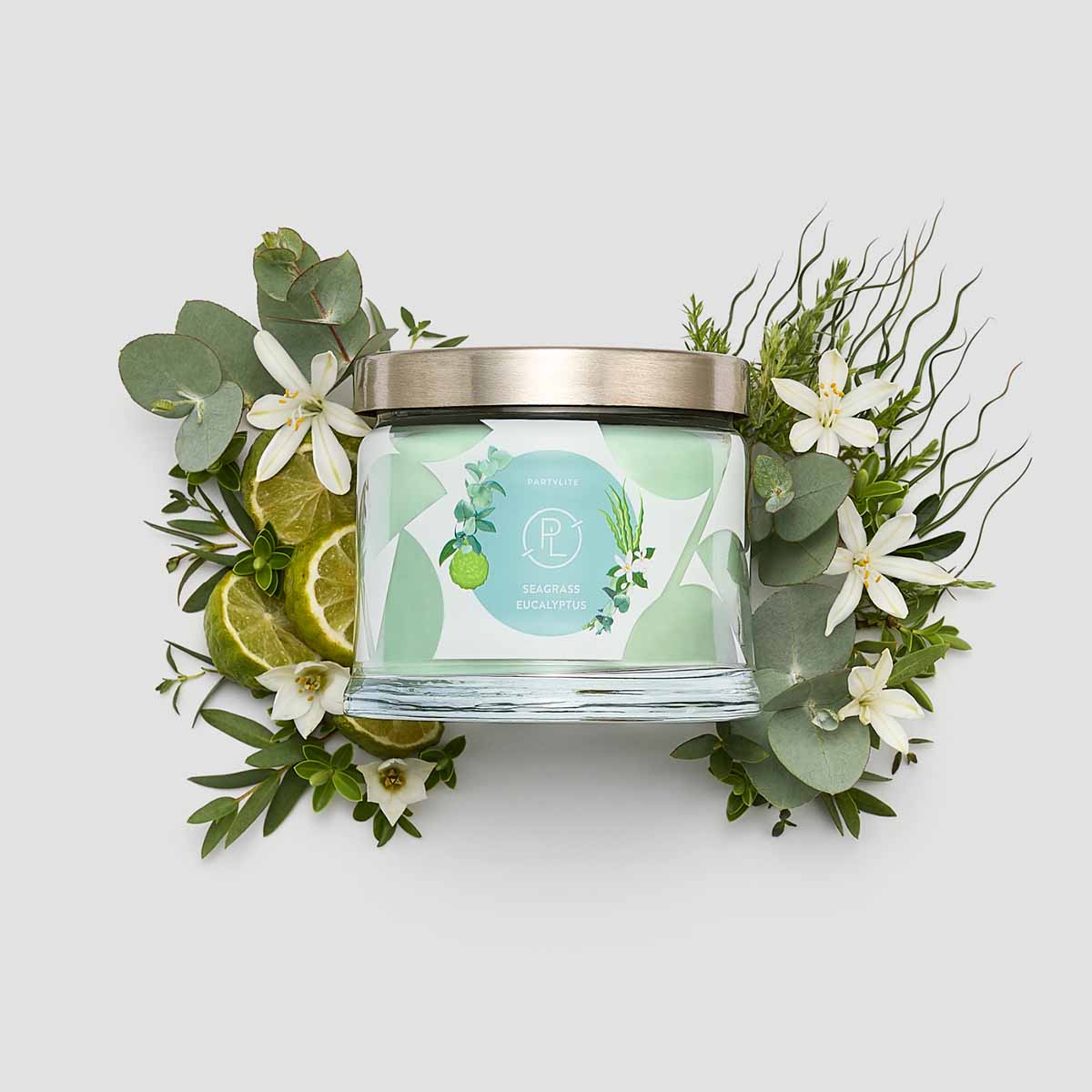 Seagrass Eucalyptus 3-Wick Jar Candle shown surrounded by flowers against a white background.