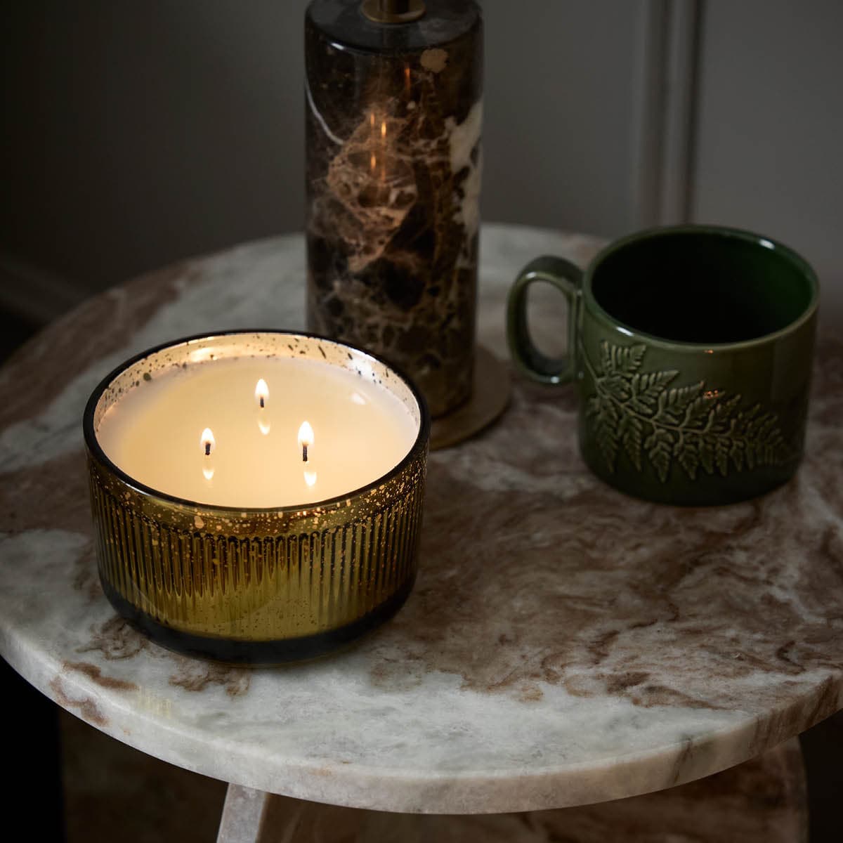 Whiskey & Oak 3-Wick Ripple Jar Candle lit on table with a ceramic mug.