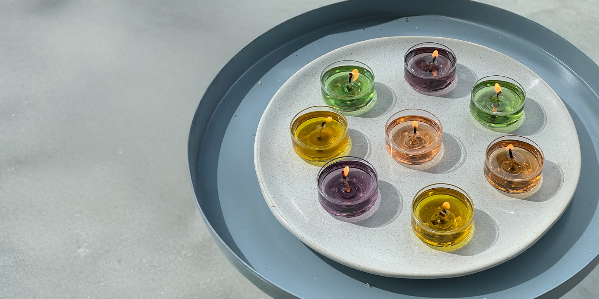 Assorted Tealights shown on a light speckled plate on a blue metal tray on a light surface