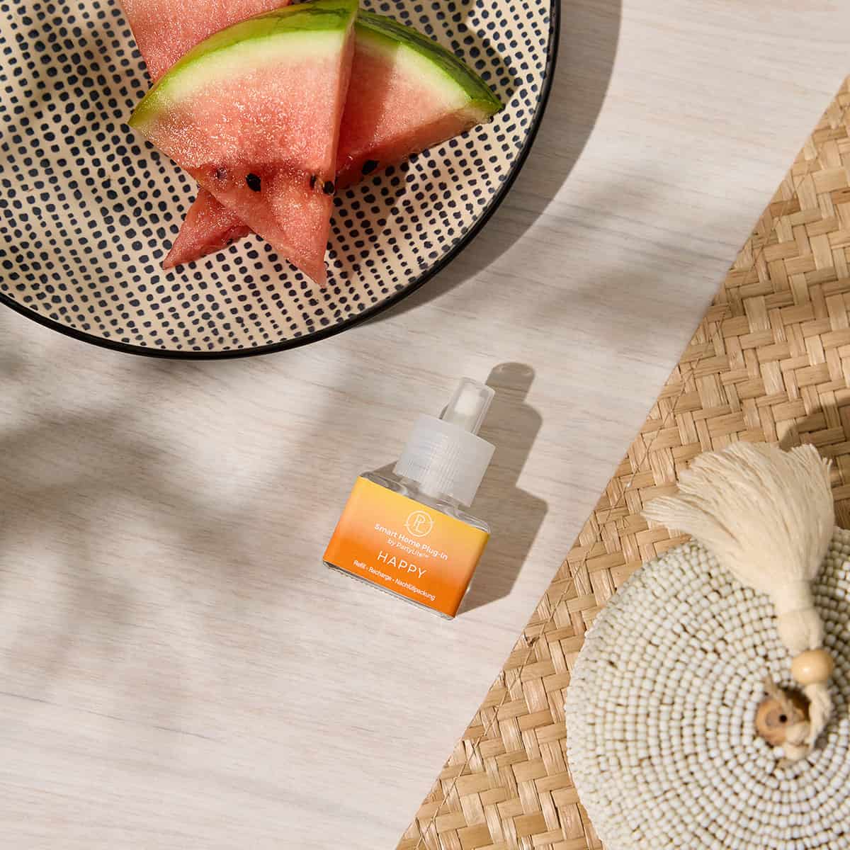 Happy Smart Home Plug In refill next to a spotted bowl with Watermelon and woven place mats against a lightly grained wooden surface