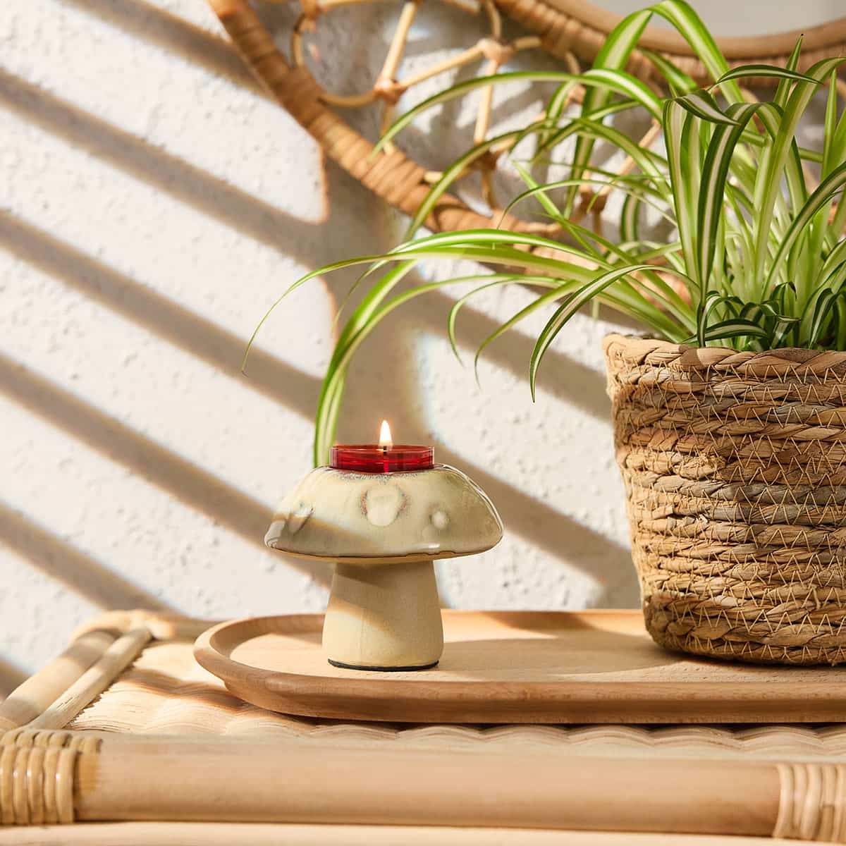Munchkin Mushroom Tealight Holder shown on a wooden tray on a wicker surface with a woven plant pot and plant next to it with a light background